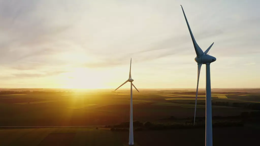 Photographie de deux éolienne et un coucher de Soleil.